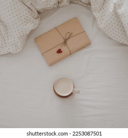 Cup of coffee with milk and gift box in bed with plaid, copy space. Flat lay, top view. morning in bed concept composition - Shutterstock ID 2253087501