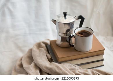 A cup of coffee and a moka pot on a few books in a cozy space. Enjoying life indoors. - Powered by Shutterstock