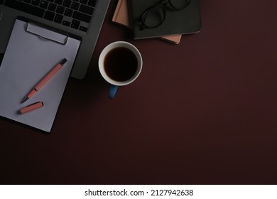 Cup of coffee, notepad and computer laptop on purple background.