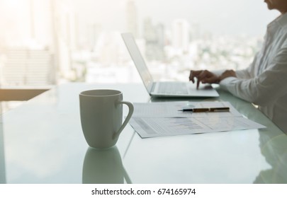 Cup Coffee on desk with women using laptop computer in office workplace. - Shutterstock ID 674165974