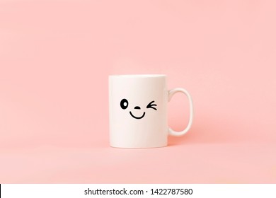 Cup Of Coffee On Pink Background With Happy Smile Face On Mug.