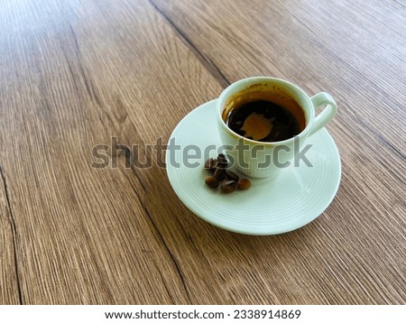 Cup of coffee on saucer and coffee beans on beautiful wooden background