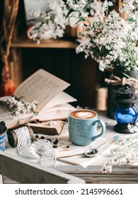A cup of coffee on the table with books, lantern and flowers. stilllife concept. selective focus