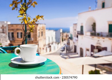 A Cup Of Coffee On Table With Italian Town At The Background