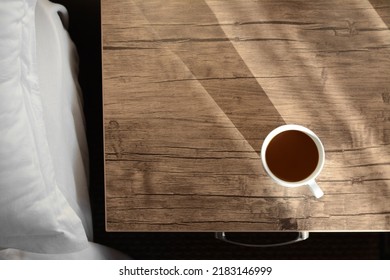 Cup of coffee on wooden night stand near bed in morning, top view. Space for text - Powered by Shutterstock