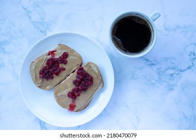 Cup Of Coffee And Peanut Butter Jelly Sandwich On White Plate On Marble Table Background. Healthy Breakfast Concept. Flat Lay, Top View, Copy Space