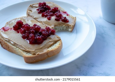 Cup Of Coffee And Peanut Butter Toasts With Berry Jelly On White Marble Table Background In The Kitchen. Making Heakthy Breakfast Process. Top View