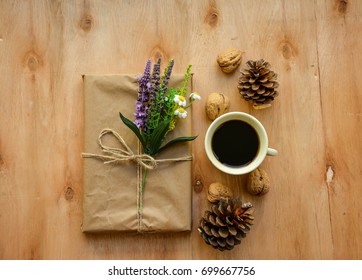 Cup of coffee with pine cones and rustic gift in paper craft on wooden table