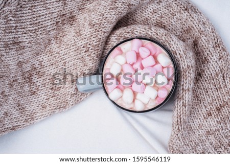 Cup of coffee with pink marshmallow on bed with warm plaid. Copy space. Flat lay, top view