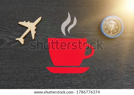 A Cup of coffee, a plane, a compass on a dark background. Morning flight, business class, airfare.