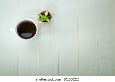 Cup Of Coffee And Small Plant In A Pot On Pastel Green Background