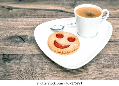 Cup Of Coffee With Smiley Face Cookie On Wooden Background. Funny Breakfast. Vintage Style Toned Picture