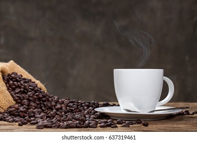 Cup of coffee with smoke and coffee beans on old wooden background.