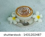 A cup of coffee with spider web pattern and flowers.
