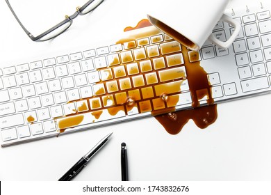 Cup of coffee spilled on keyboard office desk concept of careless clumsy or accident