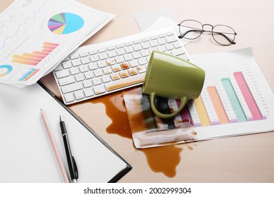 Cup Of Coffee Spilled Over Computer Keyboard On Wooden Office Desk