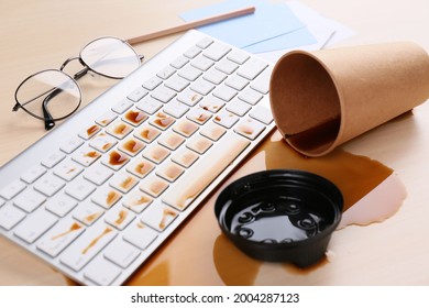 Cup Of Coffee Spilled Over Computer Keyboard On Wooden Office Desk