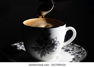 A Cup Of Coffee With A Spoon Stirring The Coffee, You Can See The Drops Falling Back Into The Cup