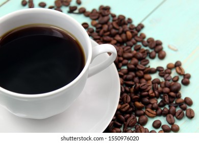 cup of coffee stands on a table with coffee beans sprinkled