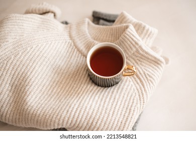 Cup Of Coffee Stay On Stack Of Knitted Textile Sweater In Bed Close Up Top View. Winter Cozy Season. 