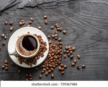 Cup of coffee surrounded by coffee beans. Top view.