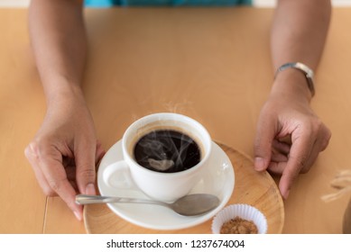 A cup of coffee in table and hand.