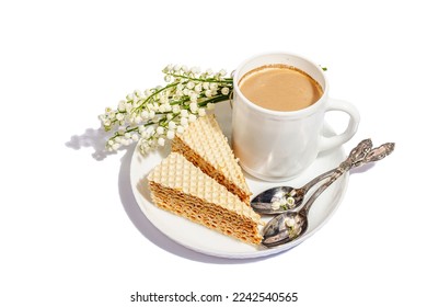 Cup of coffee and waffle cake isolated on a white background. Sweet dessert with lily valley bouquet, trendy stand, springtime breakfast concept. A hard light, dark shadow, flat lay