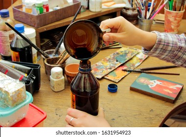 Cup Covered With Paint, With A Wood Stain Substance. Workflow Of The Artist In The Studio. Brushes And Paints On The Background In Studio.