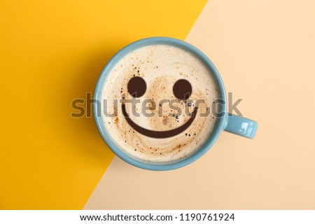 Cup of delicious hot coffee with foam and smile on color background, top view. Happy morning, good mood, inspiration