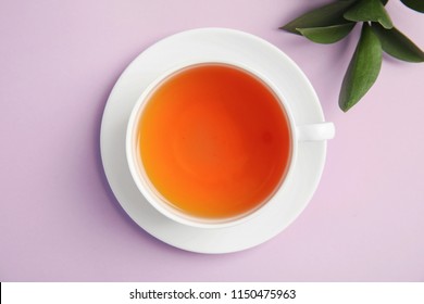 Cup Of Delicious Tea With Green Leaves On Color Background, Top View