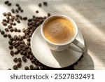 A cup of double espresso on wooden table with scattered roasted coffee beans