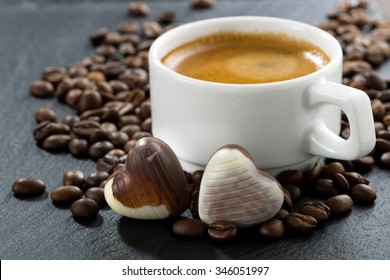 Cup Of Espresso, Coffee Beans Background And Chocolate Candies In A Heart Shape, Close-up, Horizontal