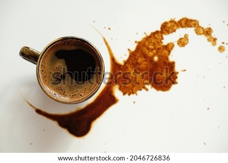 Cup of espresso on spilled coffee spots on white background, top view