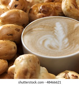 a cup of flat white with rosetta, surrounded by crusty breads