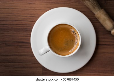 Cup Of Fresh Espresso With Cleaning Blush Of Coffee Machine On Table, View From Above