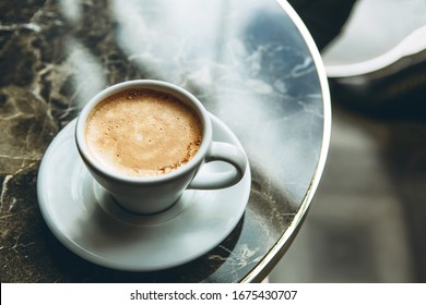 A cup of fresh fragrant morning coffee on a marble table.
