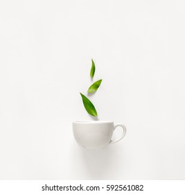 Чашка свежего зеленого чая с зелеными листьями, поднимающимися выше, концепция ароматных качеств чая