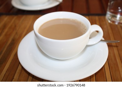A cup of fresh hot tea on the wooden table, white tea cup