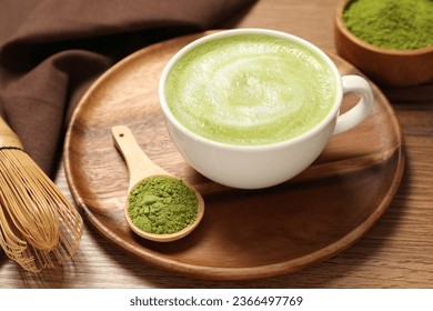 Cup of fresh matcha latte and powder on wooden table - Powered by Shutterstock