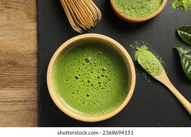 Cup of fresh matcha tea, green powder and bamboo whisk on wooden table, top view - Shutterstock ID 2368694151
