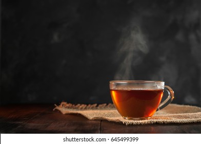 A Cup of freshly brewed black tea,escaping steam,warm soft light, darker background.