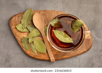 Cup of freshly brewed tea with bay leaves on grey table, top view - Shutterstock ID 2316636813