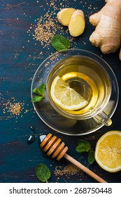 Cup of ginger tea with lemon and honey on dark blue background, top view
