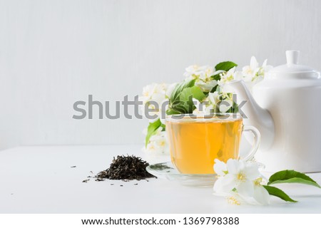 Cup of green jasmin tea white jasmine flowers, teapot on white background. Copy space. Teatime.