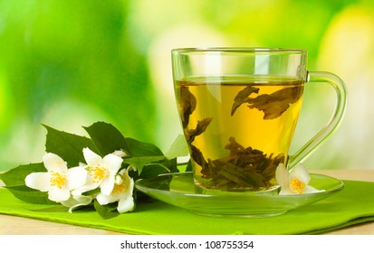 cup of green tea with jasmine flowers on wooden table on green background - Powered by Shutterstock