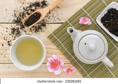 cup with green tea and teapot on wooden table background. over light