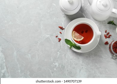 Cup Of Healthy Goji Tea With Lemon On Grey Table, Flat Lay. Space For Text