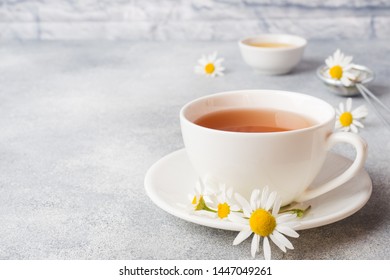 cup of herbal tea with chamomile flowers on grey table. Copy space.