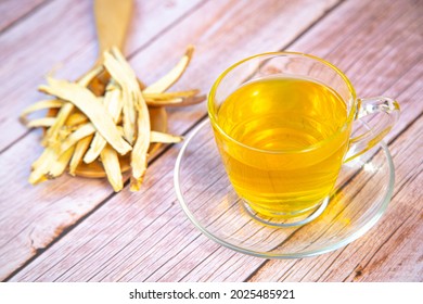 Cup Of Herbal Tea And Licorice Root On Wooden Background.