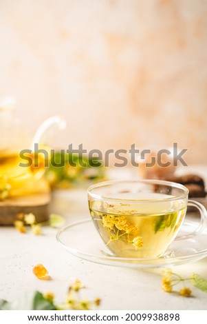 Cup of herbal tea with linden flowers on white background